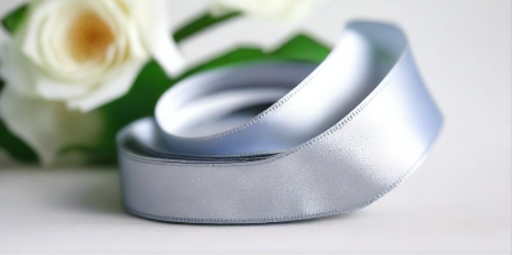 silver satin ribbon on spool on white table with white flowers