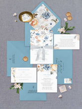 Bridgerton Lake vintage inspired floral wedding invitation featuring blue and peach flowers at the top of the design with blue coloured envelopes, floral liner, detail card, wishing well and rsvp flatlay