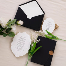 A white scalloped wedding invitation suite with floral embossed detailing and black printed text in a beautiful shape, matching black envelope with embossed envelope liner and gold wax seal on side
