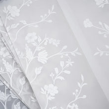 White floral damask patterned fabric with a semi-sheer overlay, shown folded diagonally.