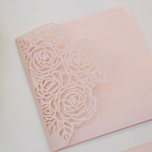 Elegant laser-cut wedding invitation with floral rose design closeup