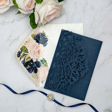 Navy blue laser-cut invitation card with a swirl patterned design featuring blue floral envelope liner