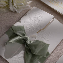 Sculptured embossed rose designed gate-fold wedding invitation, closed with sage green silk ribbon