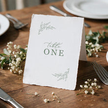 botanical beth table card featuring leaf design, printed on deckle edge paper sitting on reception table surrounded by white flowers