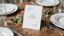 botanical beth table card featuring leaf design, printed on deckle edge paper sitting on reception table surrounded by white flowers
