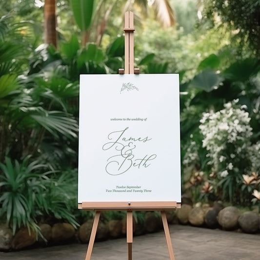 botanical beth wedding welcome sign featuring leaf design and handdrawn font script on an easel in a garden setting