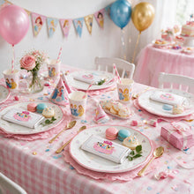 A pink and white checkered children's party table setting featuring Disney Princess themed paper plates, cups, napkins, party hats, macarons, and a wrapped chocolate bar. The scene is decorated with balloons, a banner, and a pink tablecloth in a bright indoor setting.