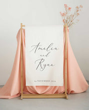 Wedding fabric linen sign with 'Amelia and Ryan' and date on a stand with pink fabric and dried flowers.