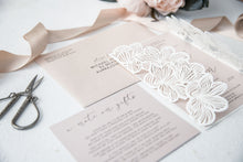 Laser-cut gate-fold wedding invitation featuring flower design on the folds shown in white with blush pink invitation suite