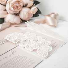 Laser-cut gate-fold wedding invitation featuring flower design on the folds shown in white with blush pink invitation side