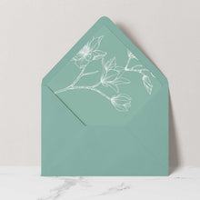 A sage green envelope with a matching floral liner featuring white line art of magnolia blossoms.