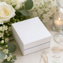 White marble tile coaster box surrounded by flowers and a candle at a wedding reception, wedding favor