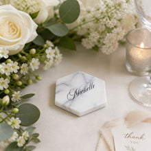 Marble tile coaster with name decal,on table, surrounded by flowers and a candle at a wedding reception