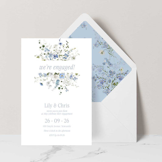 Primrose Spring is a romantic floral engagement invitation inspired by the softness of early spring gardens. Delicate hand-painted botanicals in powder blue, soft white and fresh green gently frame the invitation, creating an airy, elegant composition that feels both timeless and light. 
