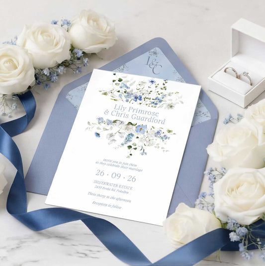 Primrose Spring Wedding Invitation suite, hand-painted botanicals in powder blue, soft white and fresh green gently frame the invitation, featuring a dusty blue envelope with matching floral liner with white rose floral scene