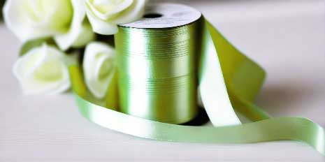autumn green satin ribbon on spool on white table with white flowers