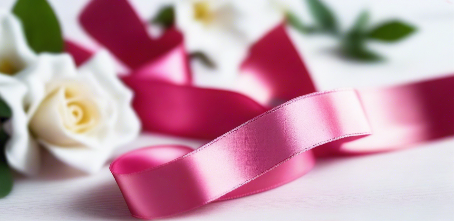 azalea pink satin ribbon on spool on white table with white flowers