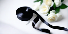 black satin ribbon on spool on white table with white flowers