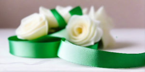 hunter green satin ribbon on spool on white table with white flowers