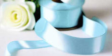 light blue satin ribbon on spool on white table with white flowers