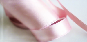light pink satin ribbon on spool on white table with white flowers