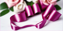 magenta pink satin ribbon on spool on white table with white flowers