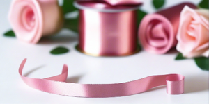 rose pink satin ribbon on spool on white table with white flowers