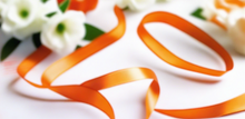 tangerine orange satin ribbon on spool on white table with white flowers