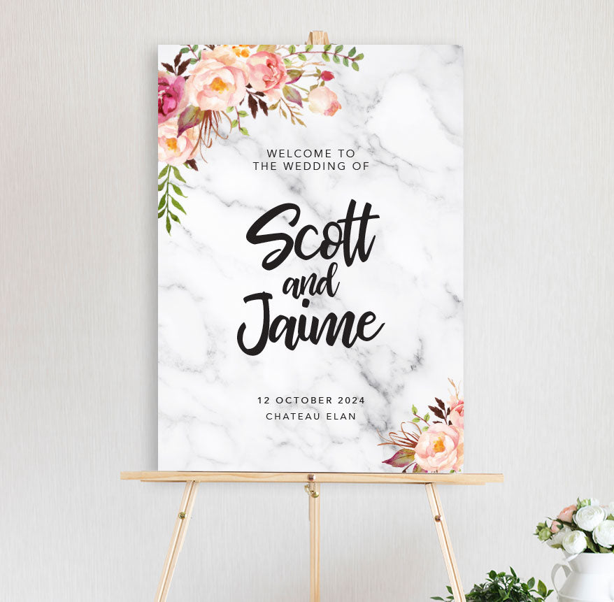 An welcome sign featuring a floral arrangement with peonies in pink and peach hues with marble background with a script font for engagement, wedding, birthday