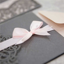 grey laser-cut invitation with pink ribbon
