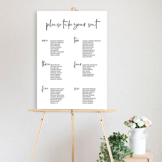 modern script black and white table seating chart sitting on a timber easel