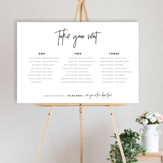 modern black and white table seating chart plan sitting on a timber easel