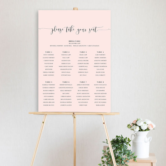 modern pink script font table seating chart sitting on a timber easel