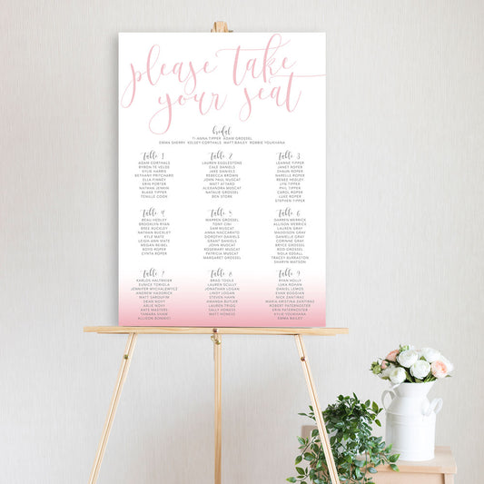 pink gradient table seating chart sitting on a timber easel