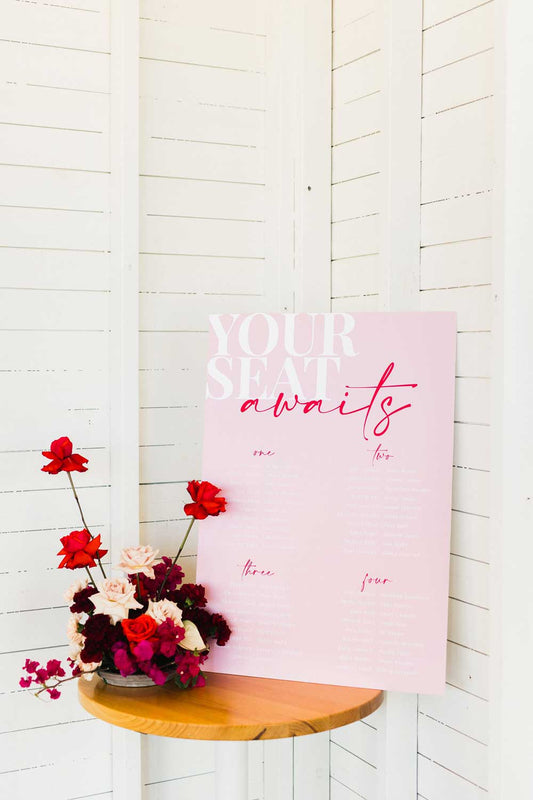 pink and red your seat awaits table seating chart neon dream collaboration sitting on a timber easel