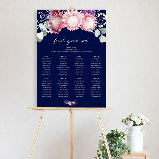 table seating chart featuring watercolour king protea and eucalyptus design with navy background sitting on a timber easel