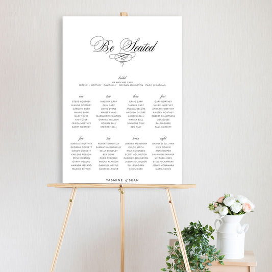 classic script table seating chart sitting on a timber easel