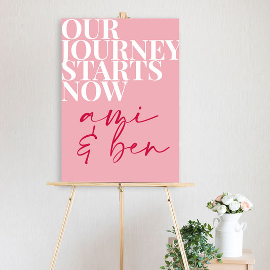 fun our journey starts now colourful red, pink and white welcome sign on timber easel