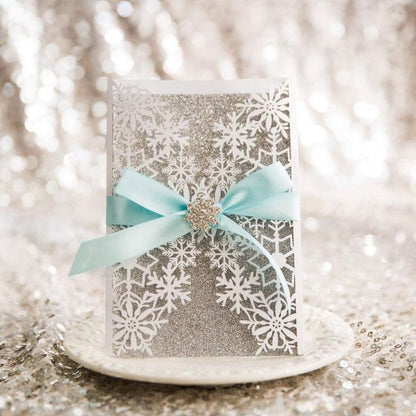 Winter Snowflake Gate Fold Laser-cut invitation in white with silver glitter backing card featuring aqua blue ribbon and snowflake cluster
