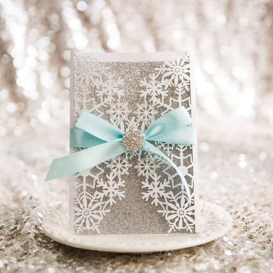 Winter Snowflake Gate Fold Laser-cut invitation in white with silver glitter backing card featuring aqua blue ribbon and snowflake cluster